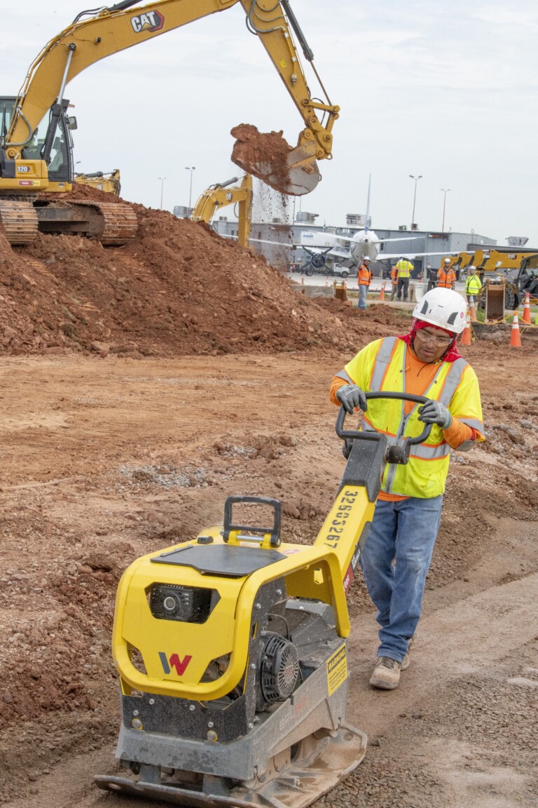 CMAC employee using a plate compactor on job site